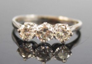 A white metal diamond three-stone ring, featuring three graduated round brilliant cut diamonds in