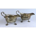 A pair of George II silver sauceboats, each of plain oval form with shaped rims and scrolling