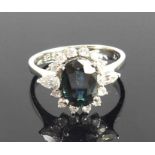 A white metal, sapphire and diamond oval cluster ring, featuring a centre oval sapphire with a