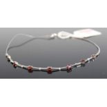 A modern white metal garnet and white sapphire set necklet, arranged as seven four-claw set oval cut