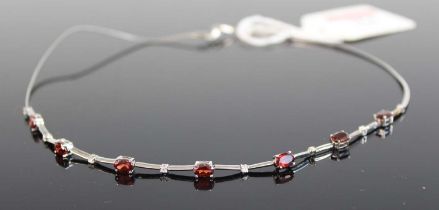 A modern white metal garnet and white sapphire set necklet, arranged as seven four-claw set oval cut