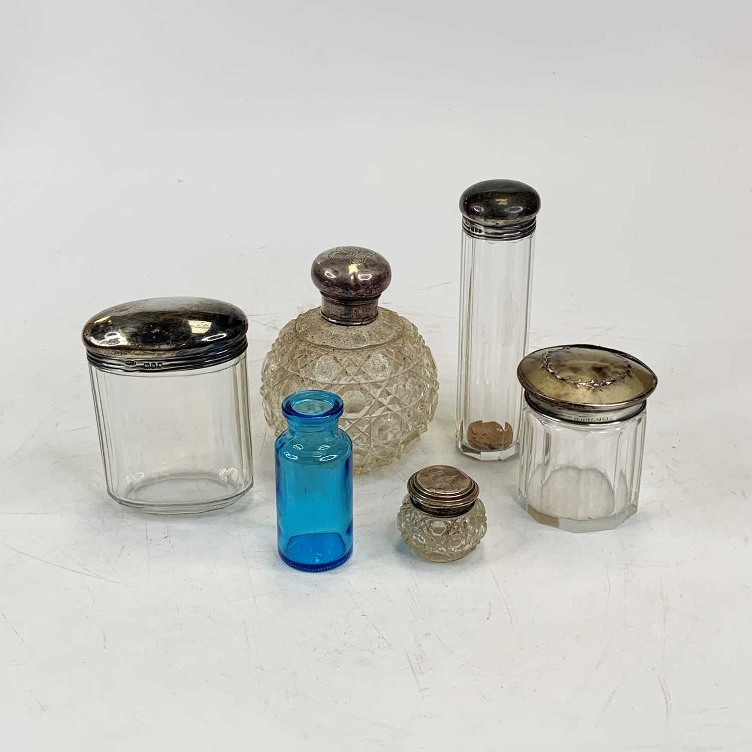 A Victorian cut glass scent bottle, having a silver lid together with four further silver lidded