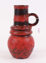 A West German pottery vase, red and black glazed, having single loop handle, h.27cm