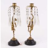 A pair of figural brass table candlesticks, each having cut glass droplets and mounted upon a