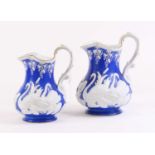 A graduated set of two Victorian relief moulded pottery jugs, each decorated with swans, largest