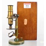 A 19th century brass monocular microscope, having a mahogany case and some slides, height of
