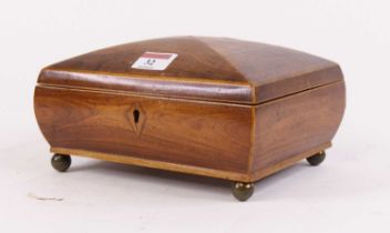 An early 19th century rosewood box, having kite shaped escutcheons standing upon four brass ball