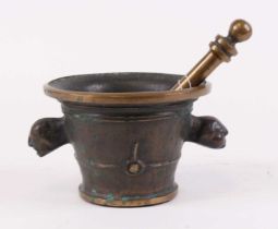 A bronze pestle and mortar, the mortar flanked by twin mask handles, height 12cm