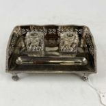 A silver plated desk stand having a raised pierced gallery, two glass inkwells, and a pen tray,