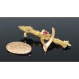 A 9ct gold and garnet set wishbone brooch, 41mm, together with 9ct gold cufflink (front only), gross