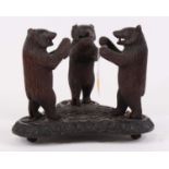 An early 20th century Black Forest carved wood model of three standing bears bears, on shaped