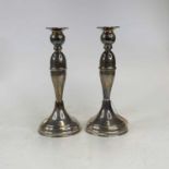 A pair of continental white metal table candle sticks each having a tapered stem each on weighted