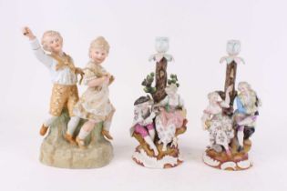 A pair of German porcelain figural table candlesticks, each h.29cm; together with a bisque porcelain