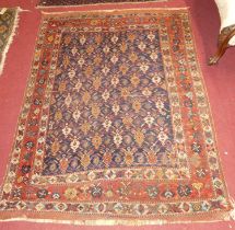 A Turkish woollen blue ground rug, the repeating central ground within trailing red ground decorated