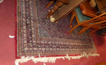 A Persian woollen red ground Tabriz rug, having a heavy floral decorated central ground, within