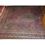 A Persian woollen red ground Shiraz rug, having a heavy floral decorated ground within trailing