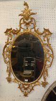 A Rococo revival gilt composition framed oval wall mirror, having a floral and pagoda decorated