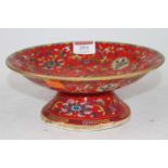 A Chinese red glazed porcelain pedestal dish, enamel decorated with chrysanthemums, bearing six