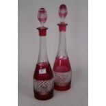 A pair of cut cranberry and clear glass decanters, and stoppers, height 41cm