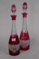 A pair of cut cranberry and clear glass decanters, and stoppers, height 41cm