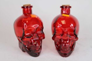 A pair of cranberry glass decanters in the form of skulls, h.17cm