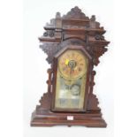 An early 20th century gingerbread type mantel clock, the chapter ring showing Roman numerals, having