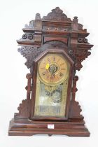 An early 20th century gingerbread type mantel clock, the chapter ring showing Roman numerals, having