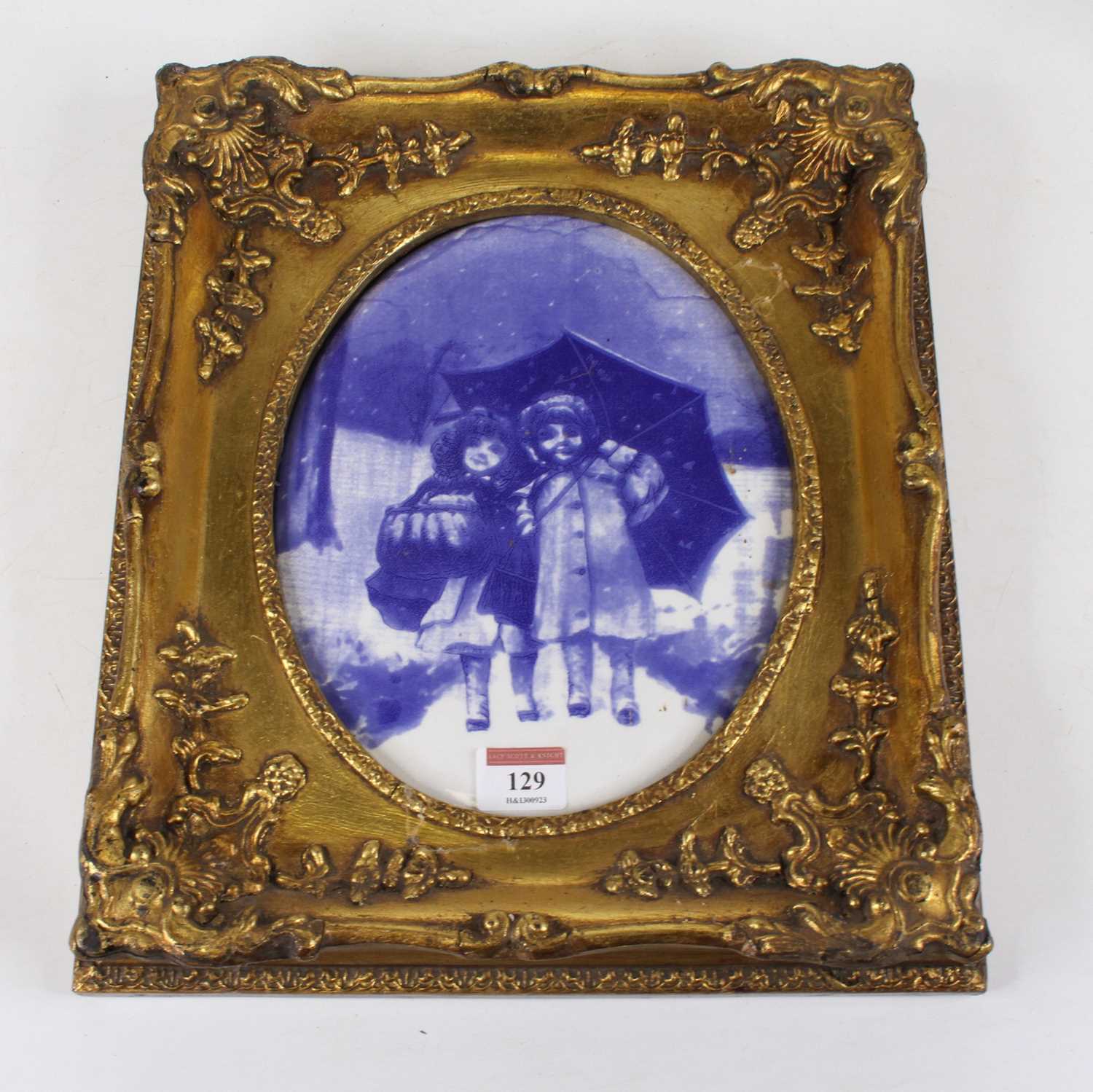 A blue and white pottery wall plaque, decorated with children, unmarked, 24 x 19cm, housed in a gilt