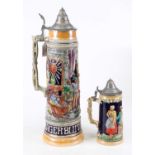 A German pottery beerstein, relief decorated with figures, h.47cm; together with another smaller (