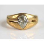 A yellow metal diamond solitaire ring, featuring an old pear cut diamond flush set within a boat