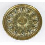 A late 19th century continental brass pedestal alms dish, the centre decorated with a portrait