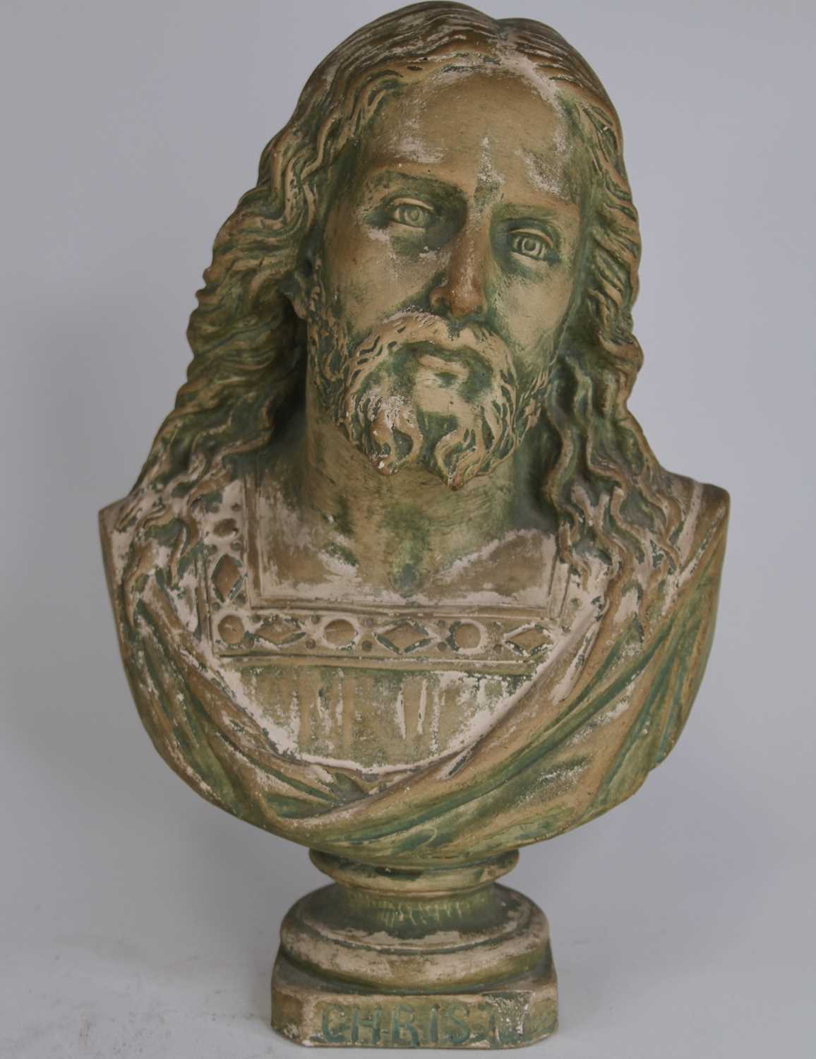 A painted pottery head and shoulders bust of Christ, h.32cm cracks to each side of the plinth
