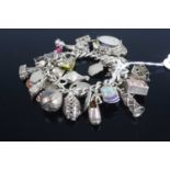 A silver curb link bracelet containing large quantity of silver and white metal charms, gross weight