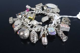 A silver curb link bracelet containing large quantity of silver and white metal charms, gross weight