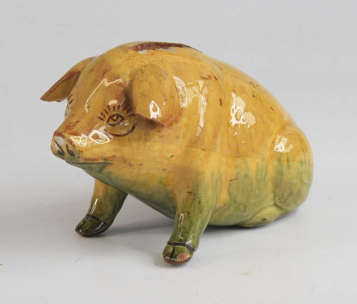 An Ewenny pottery piggy bank, shown in seated pose, having a mottled yellow and green glaze and