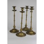 A set of four early 20th century brass candlesticks, in the manner of Benham & Froud, each having