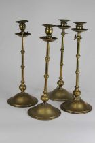 A set of four early 20th century brass candlesticks, in the manner of Benham & Froud, each having