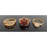 A 9ct gold cz set solitaire ring, size M; a 9ct gold garnet flower head cluster ring; and a 9ct gold