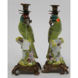 A pair of porcelain table candlesticks, each in the form of a parrot perched upon a stump, having