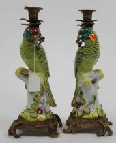 A pair of porcelain table candlesticks, each in the form of a parrot perched upon a stump, having