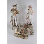 A pair of continental pottery figures of a lady and gentleman, each shown in 18th century dress on