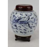 A Chinese porcelain ginger jar and cover, decorated with dragon amongst clouds, having a hardwood