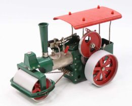 A Wilesco Old Smoky live steam traction engine comprising of green body with red canopy fitted