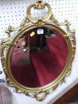 A contemporary floral pierced gilt metal framed bevelled oval wall mirror, 76 x 45.5cm