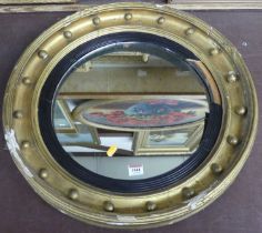 A late Victorian gilt composition circular wall mirror having ball applied frame, ebonised reeded