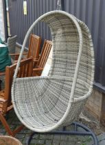 A contemporary painted tubular metal and rattan swinging garden bucket seat