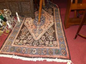 A Persian woollen brown and pink ground Shiraz rug, the lozenge central field within tramline