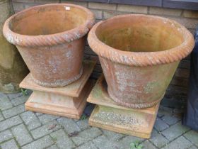 A pair of large terracotta cylindrical tapering planters, having gadrooned upper and lower edges,