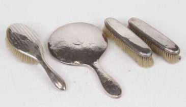 A George V silver backed hand mirror, with spot hammered finish and initialled cartouche; together