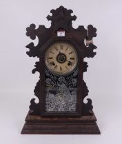 An early 20th century gingerbread type mantel clock, the papered chapter ring showing Roman